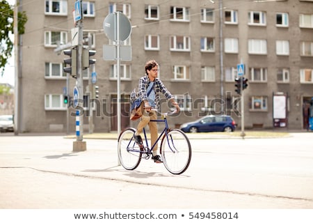 Foto d'archivio: Young Hipster Man With Bag Riding Fixed Gear Bike