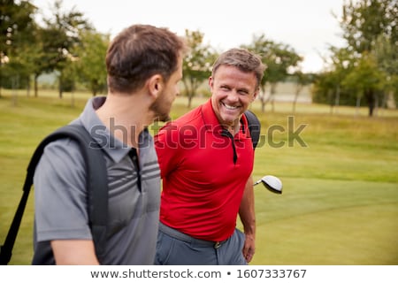 Stok fotoğraf: Two Men Walking Along Golf Course Carrying Bags