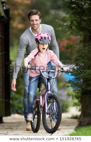 Stockfoto: Father Teaching Daughter To Ride Bike In Garden