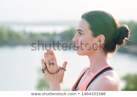 Foto stock: Side View Of Pensive Young Woman With Hair Bun Holding Mala Beads In Hands