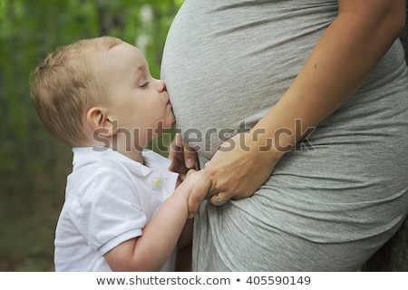 Foto stock: Happy Child Holding Belly Of Pregnant Woman In Forest