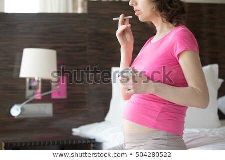 Foto d'archivio: Young Pregnant Woman Holding Cigarette On Baby Room