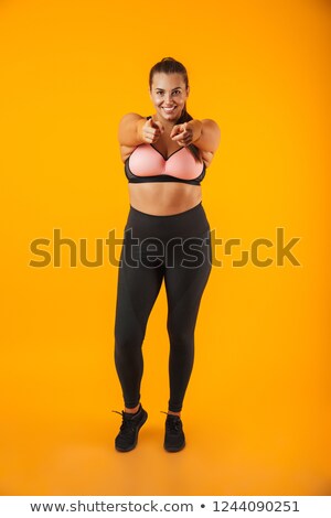 Stockfoto: Full Length Portrait Of Pretty Chubby Woman In Sportive Bra Poin