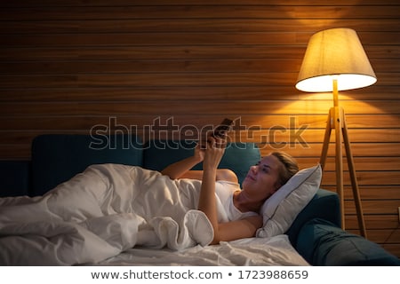 Foto stock: Woman Lying On The Bed And Using Smartphone