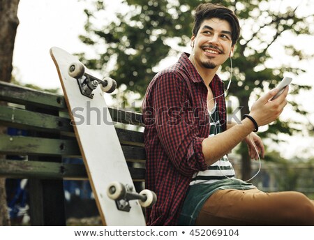 Foto stock: Smiling Young Man With Skateboard And Smartphone
