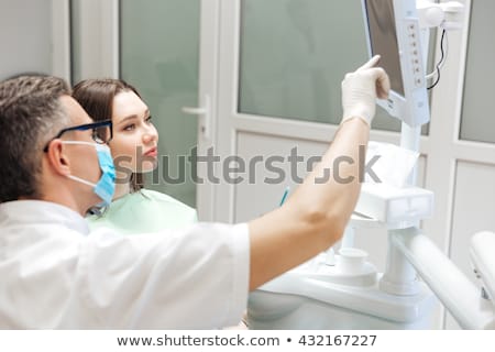 Stock photo: Male Dentist Is Reviewing Her Xray On The Computer Screen
