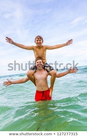 Foto stock: Brothers Enjoying The Clear Warm Water And Play Piggyback