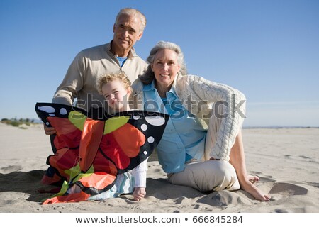 Stock fotó: Grandparents And Granddaughter Holding Kite Sitting On Beach