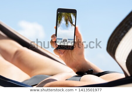 Stock fotó: Woman Lying On Hammock Taking Photo Through Mobile Phone