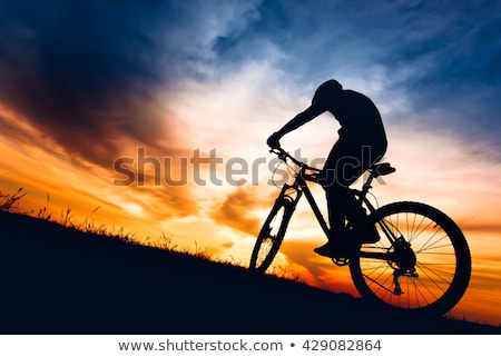 Foto stock: Silhouette Of Downhill Mountain Bike Rider At Orange Sunset