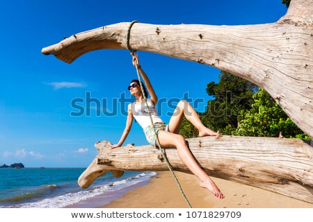 ストックフォト: Woman In Bikini Sitting On Tree Trunk At Beach