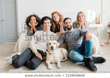 Foto stock: Two Smiling Guys With White Labrador And Pretty Girls Relaxing At Leisure