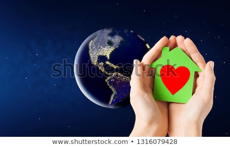 Foto stock: Hands Holding Green House Over Earth In Space