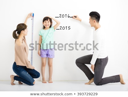 [[stock_photo]]: Measuring Height Of Cute Little Daughter