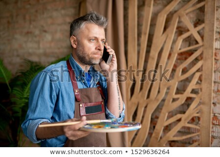 Zdjęcia stock: Irritated Or Puzzled Middle Aged Painter With Mobile Phone And Palette