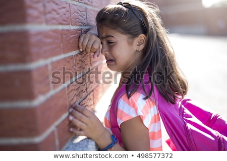 Foto d'archivio: Six Years Old School Girl Cry Beside Brick Wall