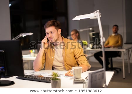 [[stock_photo]]: Man Calling On Smartphone At Night Office