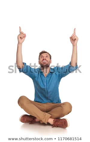 Stockfoto: Young Seated Man Pointing Up