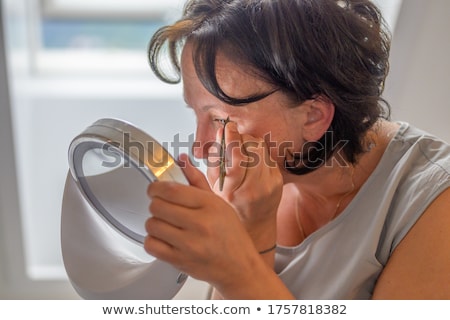 Foto d'archivio: Woman Plucking Eyebrows By The Window