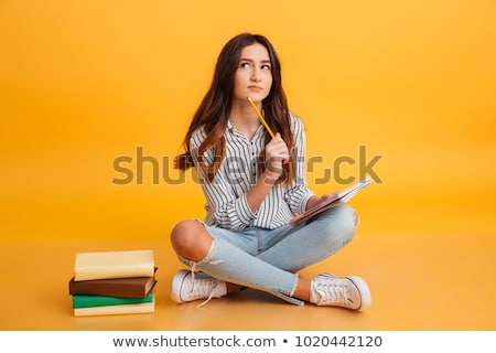 Stockfoto: A Teenage Girl Is Sitting On A Yellow Background