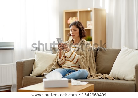 Foto stock: Sad Sick Woman In Blanket Using Smartphone At Home