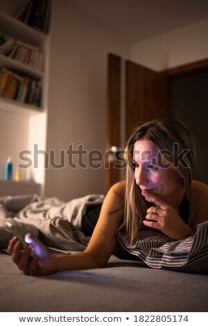 Сток-фото: Pretty Middle Aged Woman Using Her Cell Phone In Bed Before Sleep