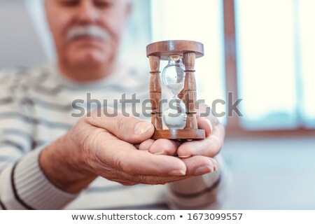 Stockfoto: Senior Man Holding Hourglass In Retirement Home Symbol For Limited Life