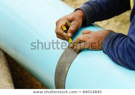 Foto stock: Plumber Marking And Cutting Pipe