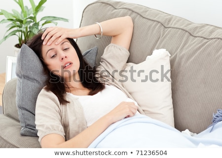 Stock fotó: Sick Woman Lying On The Sofa And Touching Her Forehead To Feel The Temperature