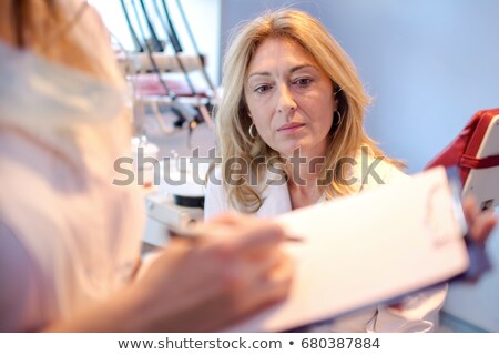 Foto d'archivio: Female Doctor Writing On Clipboard Notepad Blank Paper