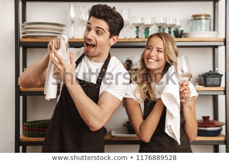 Stok fotoğraf: Excited Young Friends Loving Couple Chefs On The Kitchen Wipe Glasses