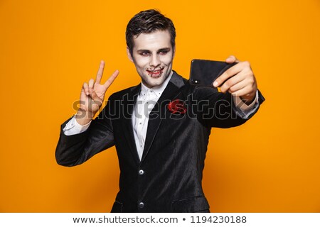 Imagine de stoc: Smiling Handsome Man Zombie Showing Peace Gesture And Making Selfie Isolated