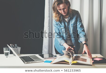 Stockfoto: Young Woman Looking Through Catalogue Of Interior Design