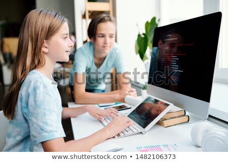 Stock photo: Pretty Youthful Girl Typing On Computer Desktop Keypad While Looking At Monitor