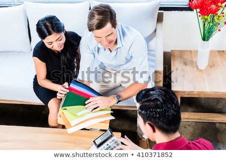 Foto d'archivio: Asian Couple In Furniture Store Choosing Material