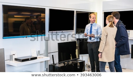 Foto stock: Salesman Showing Flat Screen Tv To Couple In Store