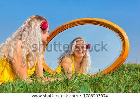 Foto stock: Woman Lying With Mirror In Flowering Meadow