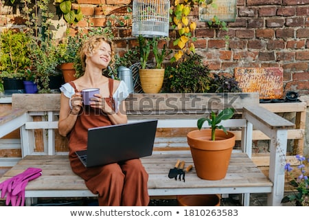 Foto d'archivio: Woman Gardener Sitting Over Flowers Plants In Greenhouse