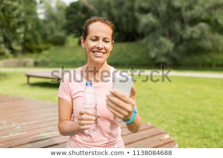 Stock photo: Woman With Smartphone Drinking Water In Park