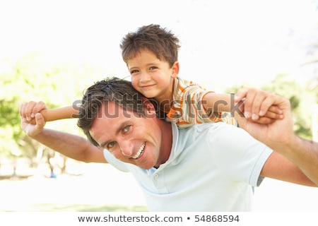 [[stock_photo]]: Father Giving Son Piggyback In Countryside