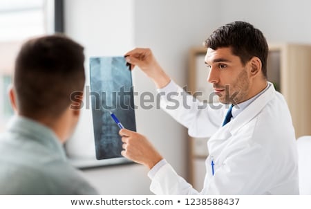 Сток-фото: A Male Doctor Showing Patients An X Ray