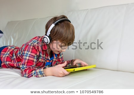 [[stock_photo]]: A Cute Little Boy Is Using A Smartphone And Headphones Lying On A Deckchair By The Pool Primary Edu