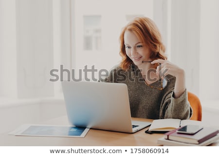 Stockfoto: Satisfied European Female With Ginger Hair Types Information On Laptop Computer Has Glad Facial Ex