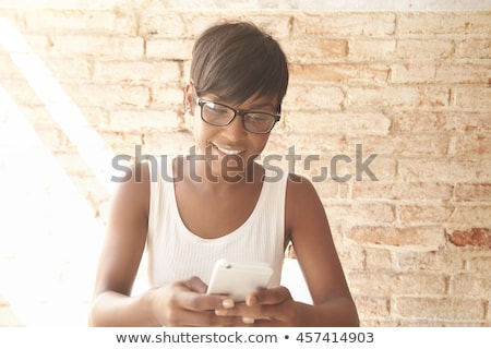 Stok fotoğraf: A Young Smiling Woman Is Texting On Her Mobile Phone Against A White Background