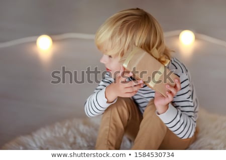 Stock foto: A Blond Haired Boy Against The Background Of Luminous Light Bulbs Is Trying To Guess Which Gift Is I
