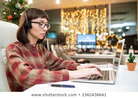 Stock foto: Young Serious Female Operator Typing On Laptop Keypad While Organizing Work