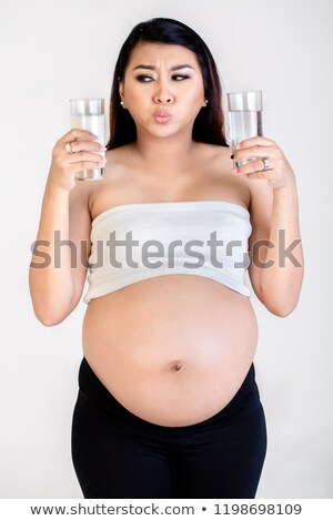 Foto stock: Confused Pregnant Woman Holding Milk And Water Glass