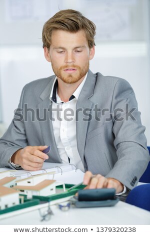 Foto d'archivio: Real Estate Agent Holding Key Above Small House Model On The Tab