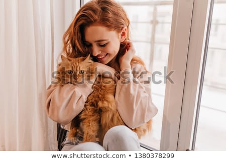 Сток-фото: Cheerful Woman Holding Red Cat And Laughing At Home