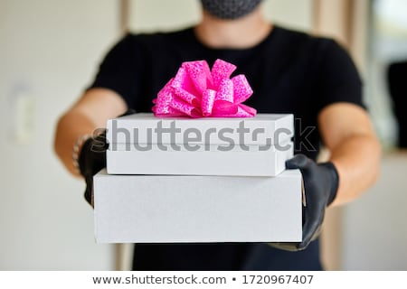 Stockfoto: Courier Man Contactless Delivery Presents Gift Box During A Coronavirus Epidemic